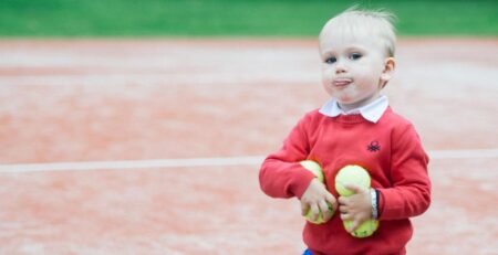 Tennis lastele: Punase kampsuniga poiss kunstmuru kattega tenniseväljakul