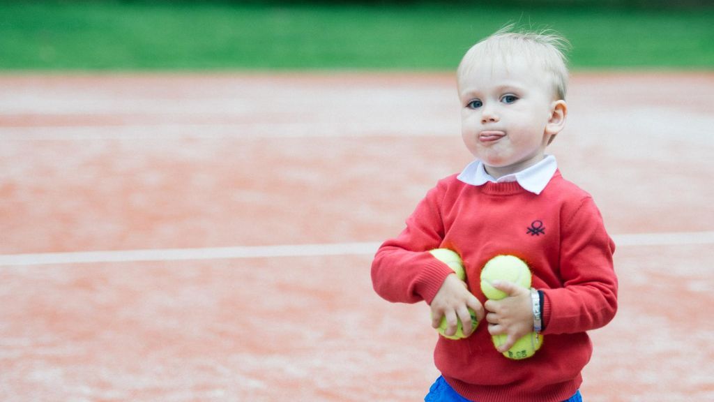 Tennis lastele: Punase kampsuniga poiss kunstmuru kattega tenniseväljakul